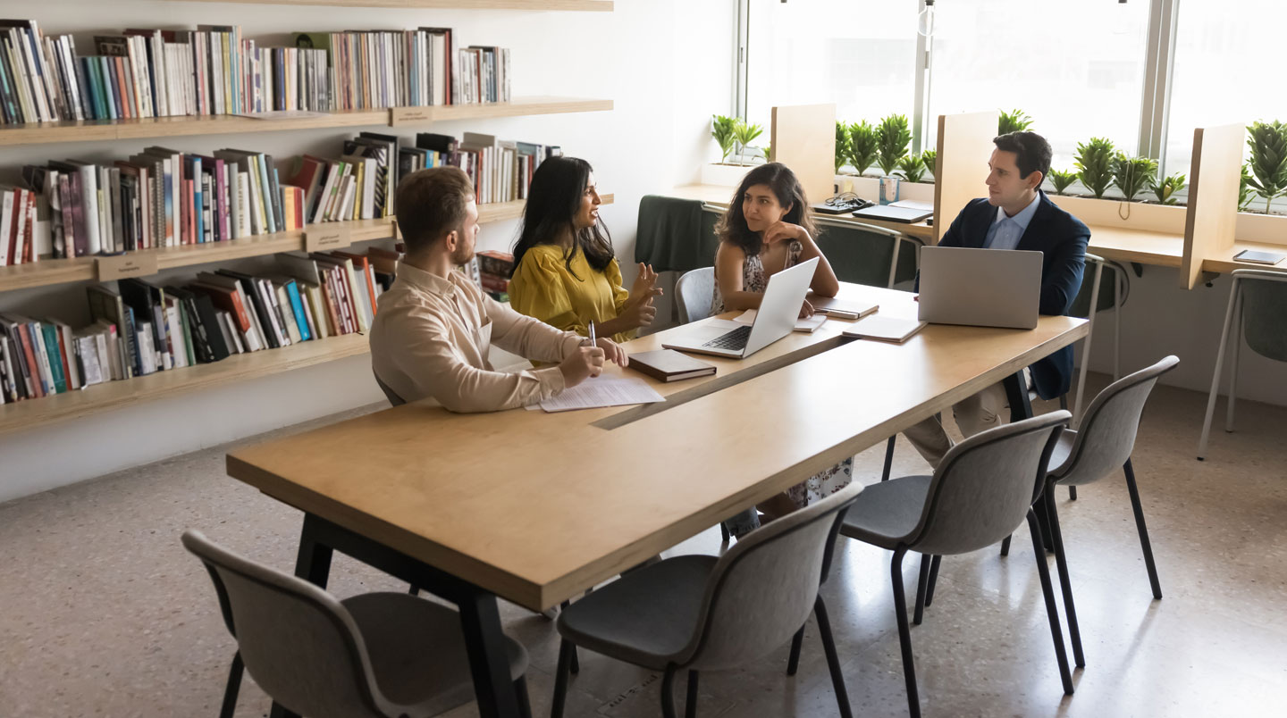Gros plan d'un carnet de notes ouvert avec un schéma collaboratif esquissé à la main, stylo posé à côté, sur une surface en bois moderne claire avec arrière-plan flouté